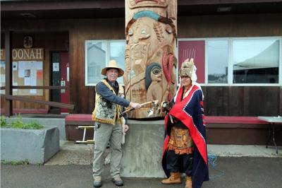 2 men in front of totem pole
